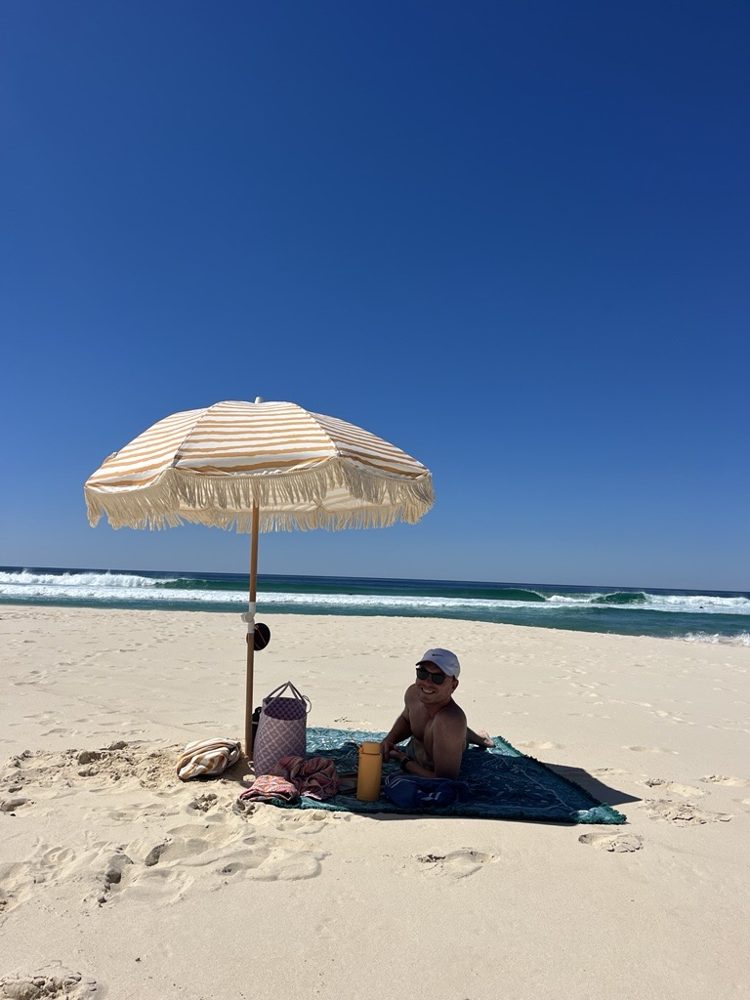 Steve under a striped beach umbrella at Blueys Beach